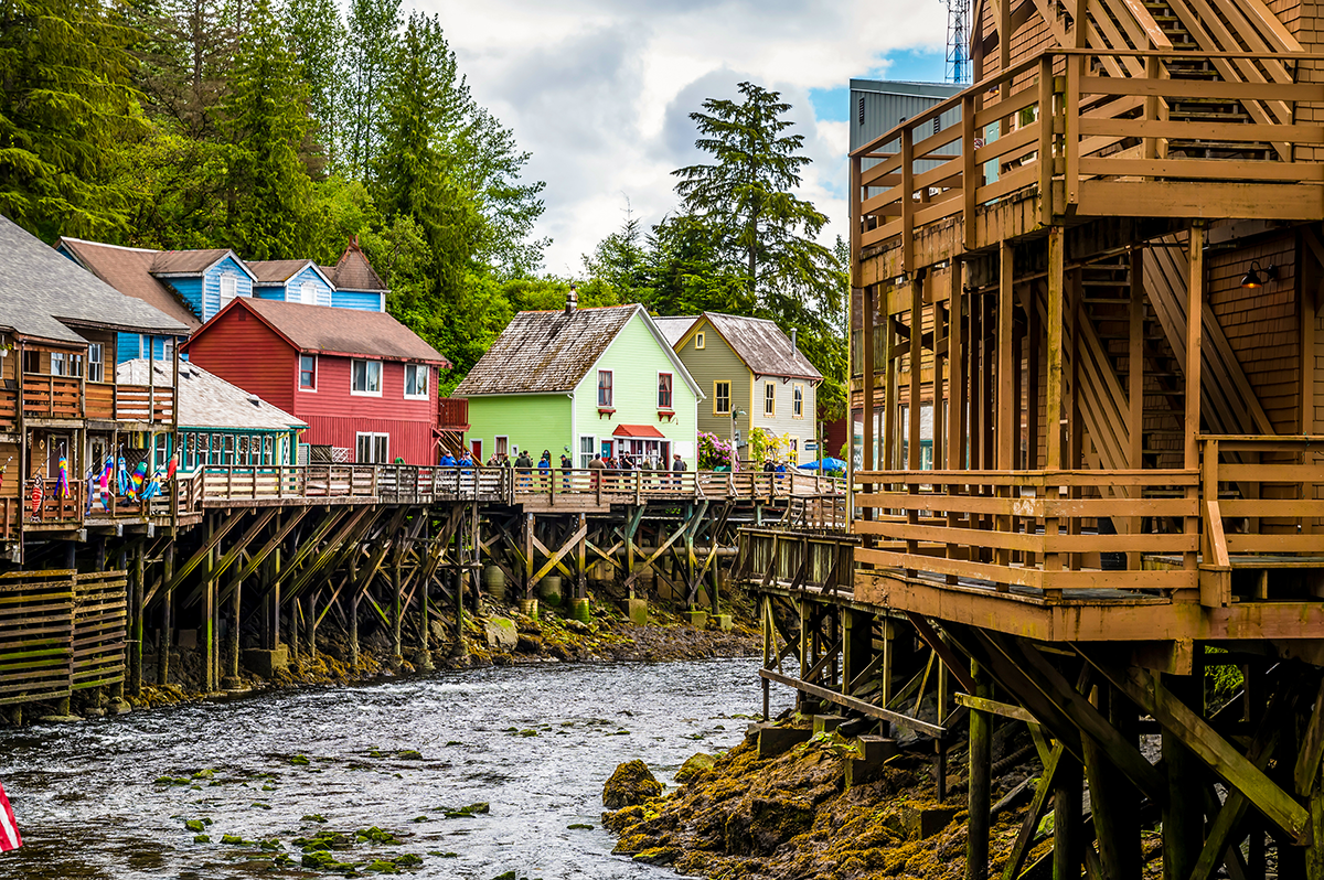 Colorful buildings line Creek Street in Ketchikan above a narrow waterway supported by wooden stilts.