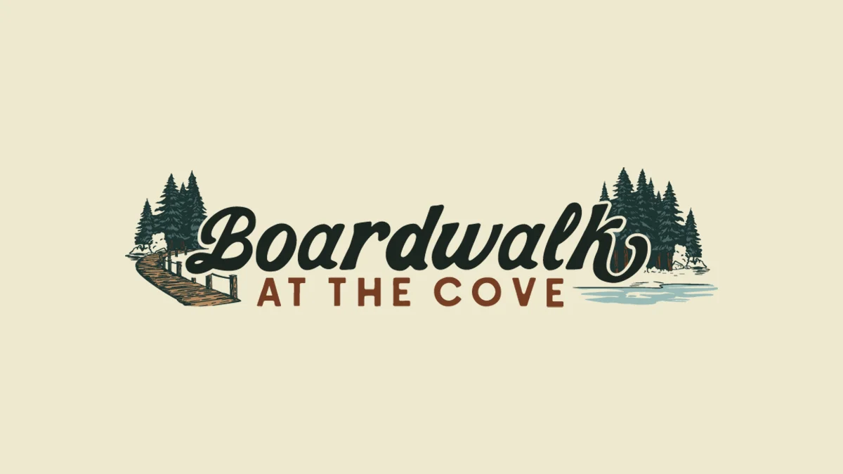 Logo for 'Boardwalk at the Cove' with a wooden boardwalk on the left, trees, and a blue cove on the right in vintage typography.